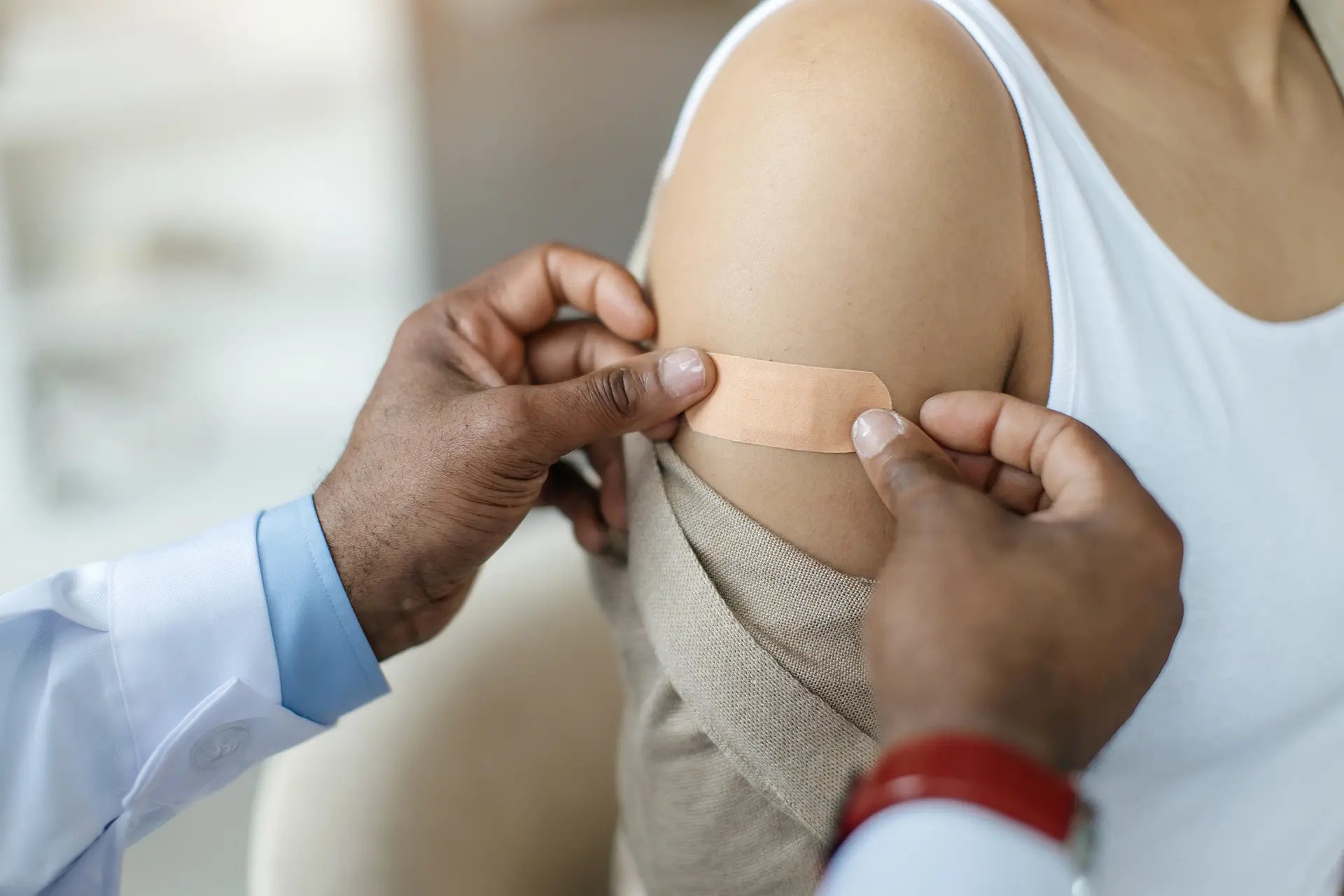 close up of a doctor putting on a bandaid after an immunization